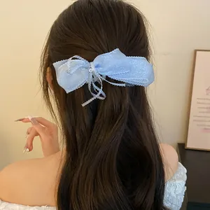 Detail view of a light blue mesh bow banana hair clip styled on a model's wavy hair