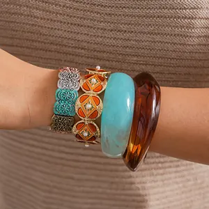 Close-up of stacked retro metal oil-drip bracelets and colorful resin bangles on wrist