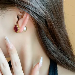 Close-up detail of 18k gold plated clover pearl earrings with a vintage red velvet finish.