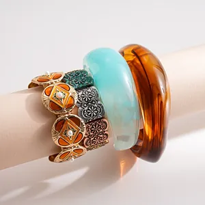 Detailed macro view of vintage metal enamel stretch bracelet and thick resin bangles set