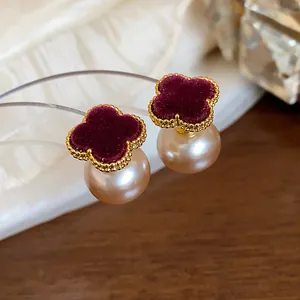 Macro detail of French retro flower pearl stud earrings featuring burgundy velvet texture