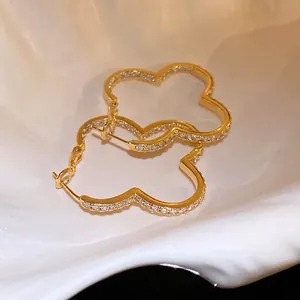 Elegant gold-plated clover hoop earrings with sparkling zircon inlay on shell background