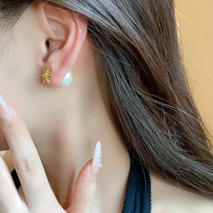 Detail of an 18k gold plated flower stud earring with a pearl backing on a model