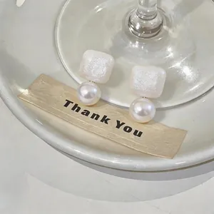 Detailed close-up of French style pearl drop earrings with white glitter square studs