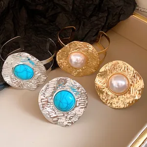 Detailed macro view of vintage hammered metal cuff bracelets with pearl and turquoise