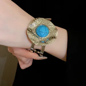 Close-up of vintage gold hammered cuff bracelet with a large turquoise stone.