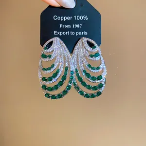 Detailed view of luxury multi-layer shell earrings with green emerald CZ stones