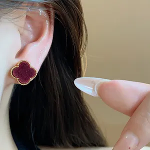 Close-up of French vintage 18k gold plated clover earring with red velvet texture