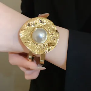Detailed macro view of a vintage hammered gold cuff bangle with a large central pearl