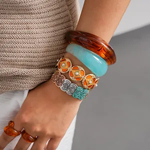 Detailed view of stacked layered bohemian metal stretch bracelets and thick resin bangles