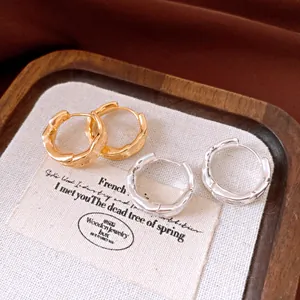 Detailed close-up view of 18k gold plated and silver wrinkled hoop earrings on a tray