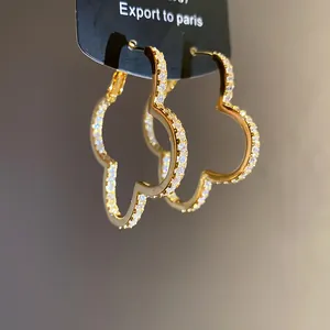 Macro view of luxury gold-plated four-leaf clover hoop earrings with sparkling zircon stones