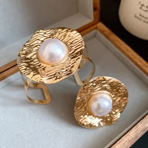 Detail shot of vintage style gold crumpled metal jewelry set with elegant pearls.