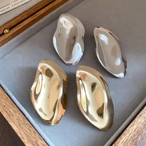 Nahaufnahme unregelmäßiger metallischer ovaler Ohrstecker in Gold und Silber Finish