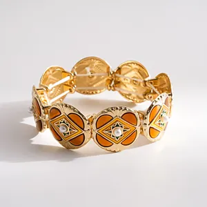 Macro view of vintage gold bracelet featuring orange enamel details and small pearls