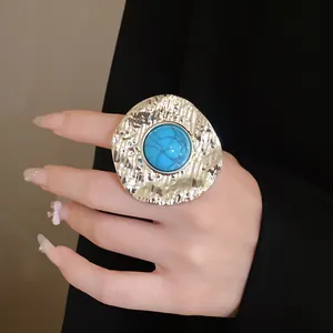 Close-up of a vintage pleated metal ring with a blue turquoise-style stone on a hand