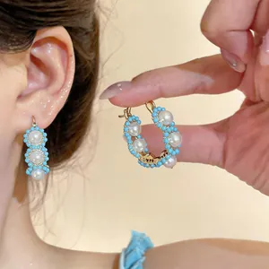 Detailed view of elegant gold-plated hoop earrings with white pearls and turquoise beads