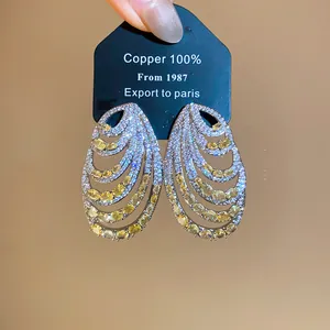 Close-up of stylish multilayer spiral earrings set with sparkling yellow and white zircons.