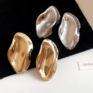 Nahaufnahme metallischer unregelmäßiger ovaler Ohrstecker mit Gold- und Silber-Finish