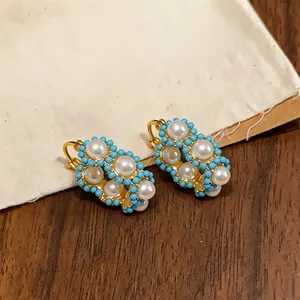 Macro detail view of 18k gold plated hoop earrings with pearls and turquoise beads