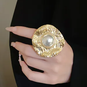 Close-up of a vintage hammered gold metal ring featuring a large central pearl.