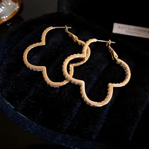 Close-up view of elegant golden clover hoop earrings adorned with shimmering zircon stones