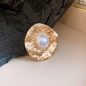 Close-up view of a vintage gold hammered ring featuring a central white faux pearl detail