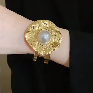 Detailed shot of hammered gold-tone cuff bracelet with a large central pearl inlay