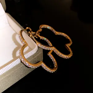 Close-up macro view of luxury gold clover hoop earrings featuring sparkling pavé zircons