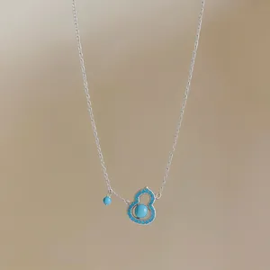 Macro view of a silver-plated necklace featuring a turquoise gourd-shaped pendant