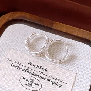 Close-up of elegant silver-plated wrinkled hoop earrings in a wooden jewelry box.