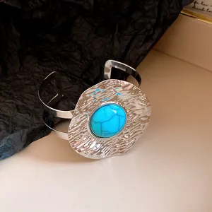 Detail view of a vintage style hammered silver cuff bracelet featuring an oval turquoise stone