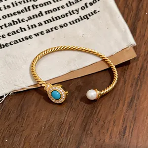 Close-up of 18k gold plated twisted cable bangle with pearl and turquoise detail