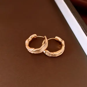 Close-up of 18k gold plated wrinkled hoop earrings showing fine texture and metallic luster.