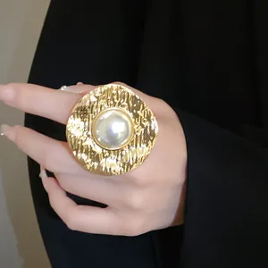Detail view of a vintage gold-tone wrinkled metal ring with a central white pearl
