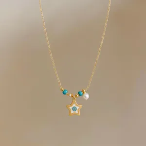 Close-up of 18k gold plated star pendant necklace with pearl and turquoise beads detail