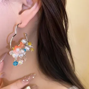 Elegant silver needle earrings featuring pearls and colorful flower pendants worn by model.