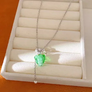 Close-up of green resin grape pendant necklace with delicate white pearl accents.