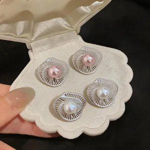 Close-up of pink and white pearl stud earrings with silver spiral flower design
