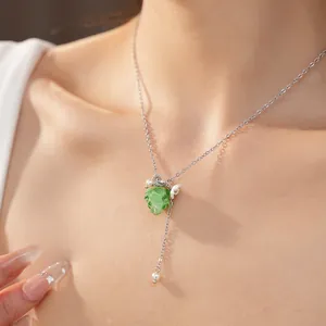 Close-up of green resin grape pendant with pearl and flower details on silver chain.