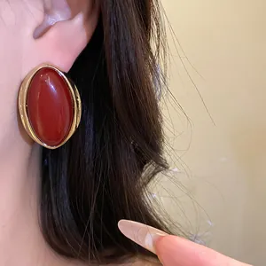 Primer plano de un pendiente de botón ovalado de resina roja de estilo vintage francés