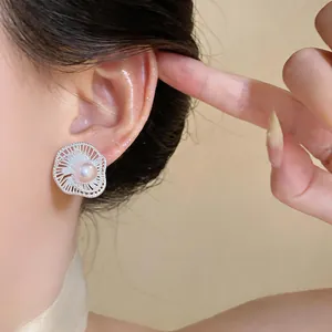 Detail shot of silver flower stud earrings with central pearl on Asian model's ear