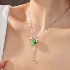 Close-up detail of green resin grape pendant with pearl accents on a fine silver necklace chain