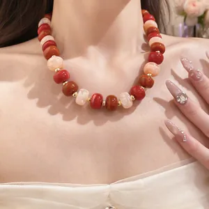 Close-up detail showing the textures of red and cream geometric beads on a handmade necklace