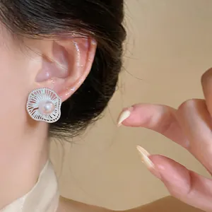 Detailed close-up showing an elegant silver flower pearl stud earring on a model's ear