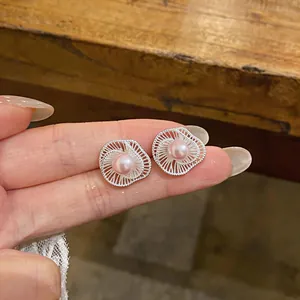 Detail showing pink pearl centered in circular silver woven flower stud earrings.