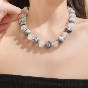 Detailed view of handmade geometric marble and translucent white beaded necklace on model