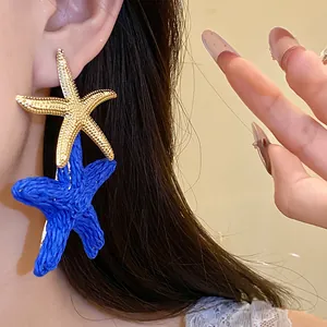 Primo piano della clip per orecchio a stella marina in rafia blu e metallo dorato