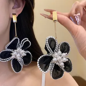 Close-up detail of elegant organza flower dangle earrings featuring pearl embellishments.
