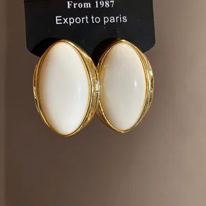 Primer plano de pendientes ovalados de resina estilo vintage francés con borde dorado